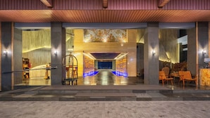 Un vestíbulo de hotel con diseño moderno, que cuenta con un mostrador de recepción, zona de estar y una pared decorativa con un mural.