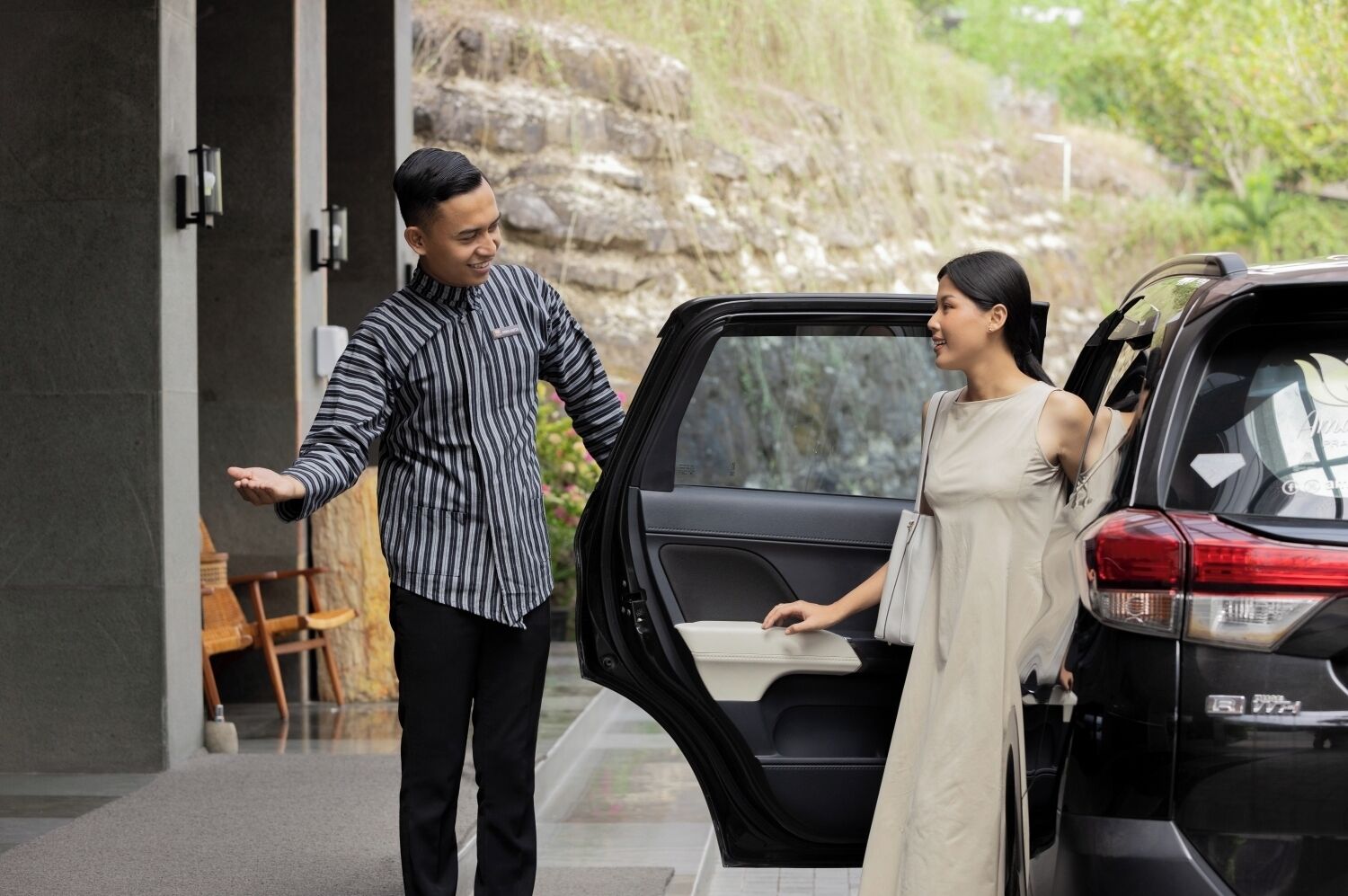A man and a woman standing by a car with an open door, suggesting a possible car service or pickup scenario.