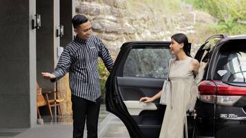 A man and a woman standing by a car with an open door, suggesting a possible car service or pickup scenario.