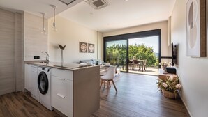 Eine moderne Küche mit integriertem Wasch- und Trockner, einem Essbereich mit großem Fenster und Blick ins Freie.
