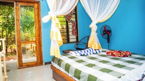 A room with a bed, a fan, and a window with curtains. - Z-VILLAGE LODGE (Jambiani)