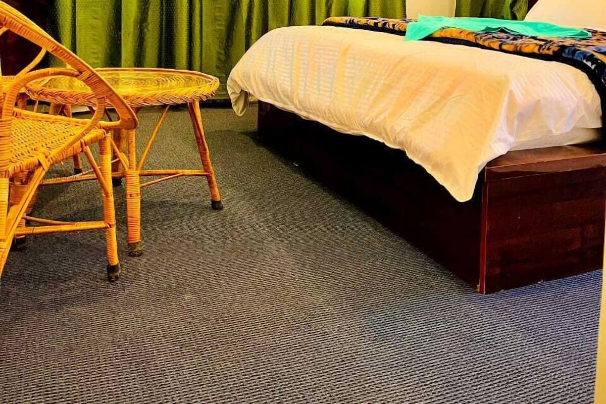 A hotel room with a bed, a chair, and curtains.