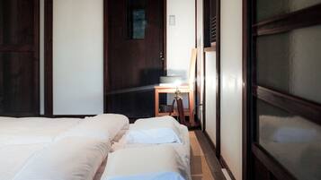 A hotel room with a wooden ceiling, a large window, and a bed with white linens.