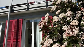 A two-story house with a red roof, white siding, and red shutters. - Holiday Home 'Kunterbunt' with Private Terrace, Shared Garden and Wi-Fi (Lindau)