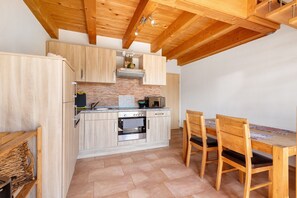 Uma cozinha com armários de madeira, painel de backsplash de tijolos e uma mesa de jantar com cadeiras.