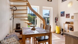 A modern kitchen with a wooden staircase, a dining table with chairs, and a yellow water heater.