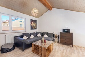 Uma sala de estar moderna com um sofá modular, uma mesa de centro de vidro, um armário de madeira e um radiador.