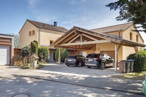 Un immobile residenziale con garage coperto, due auto parcheggiate all'interno e cielo sereno.