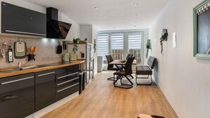 Een moderne keuken met donkere kastjes, een houten aanrechtblad en een eethoek met een tafel en stoelen.