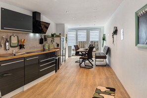 A modern kitchen with dark cabinetry, a wooden countertop, and a dining area with a table and chairs.