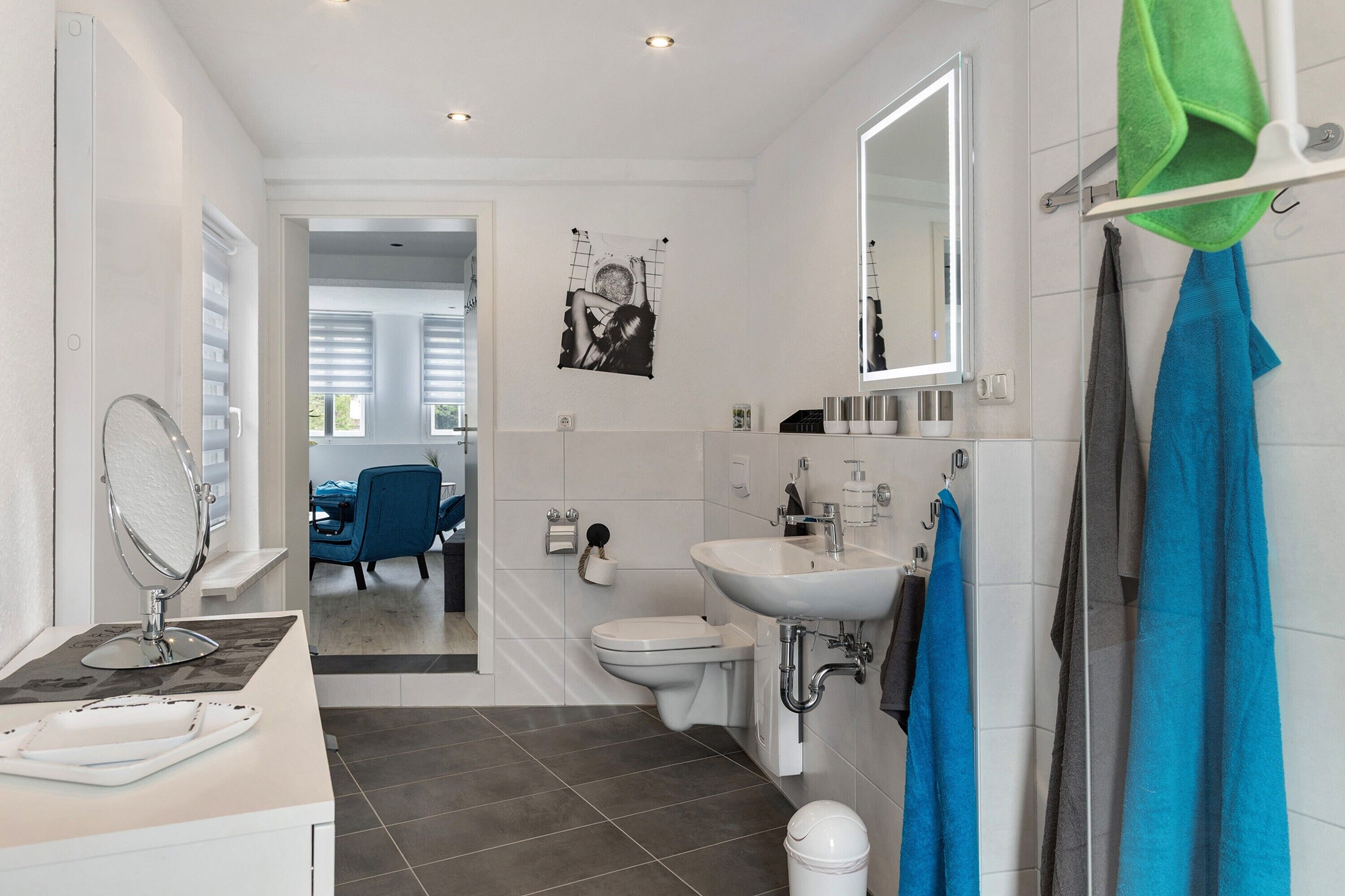 A modern bathroom with a sink, mirror, toilet, and shower.