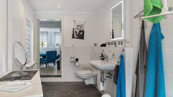 A modern bathroom with a sink, mirror, toilet, and shower.