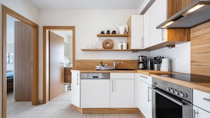 A modern kitchen with white cabinets, wooden countertops, a built-in oven, and a dishwasher. - Apartment 'Schilfbrise' with Balcony and Wi-Fi (Wunstorf)