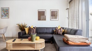 A modern living room with a sectional sofa, a coffee table, and a large window with curtains. - Apartment 'Schilfbrise' with Balcony and Wi-Fi (Wunstorf)
