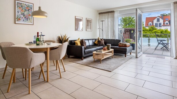 A modern living room with a dining area, a sofa set, and a view of the outside. - Apartment 'Schilfbrise' with Balcony and Wi-Fi (Wunstorf)