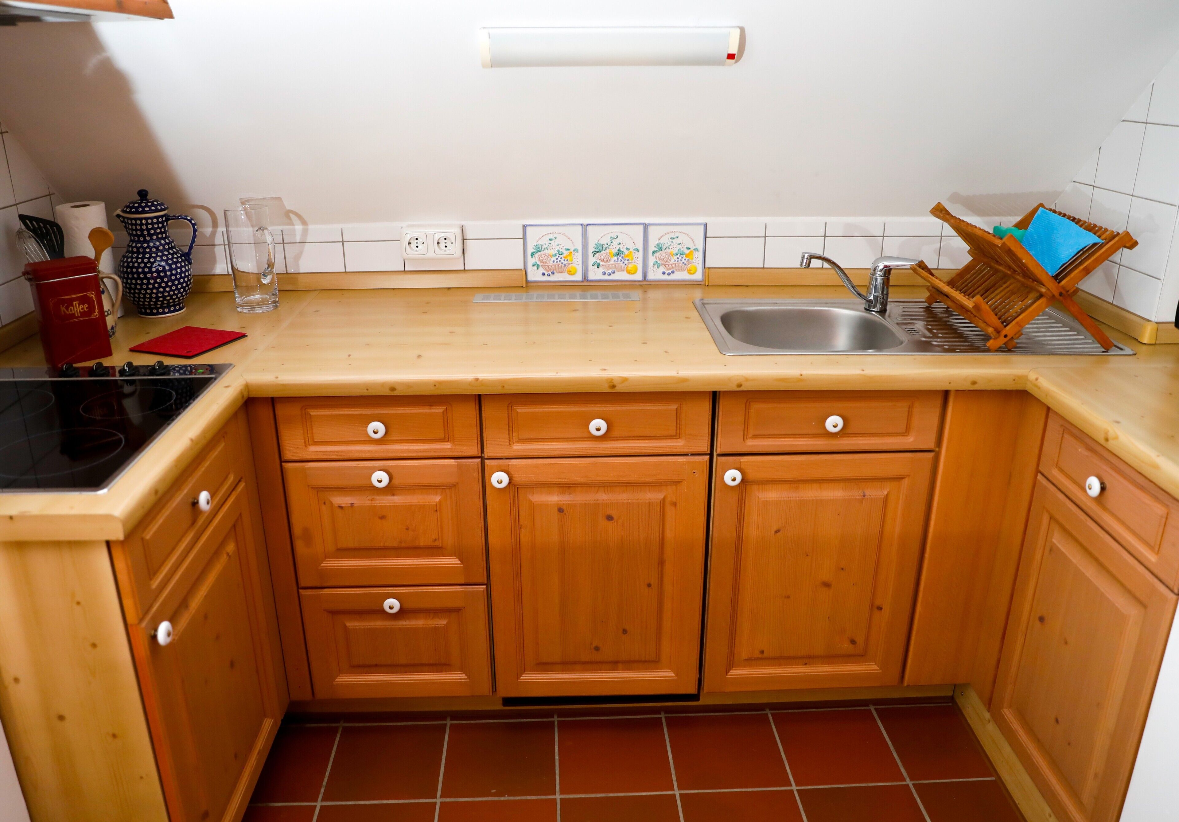 A kitchen with wooden cabinets, a sink, a coffee maker, and a tea kettle.