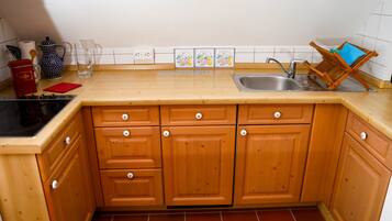A kitchen with wooden cabinets, a sink, a coffee maker, and a tea kettle.