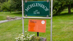 Une enseigne portant le nom « MUHLENHOF 1734 » et une plaque placée en dessous.