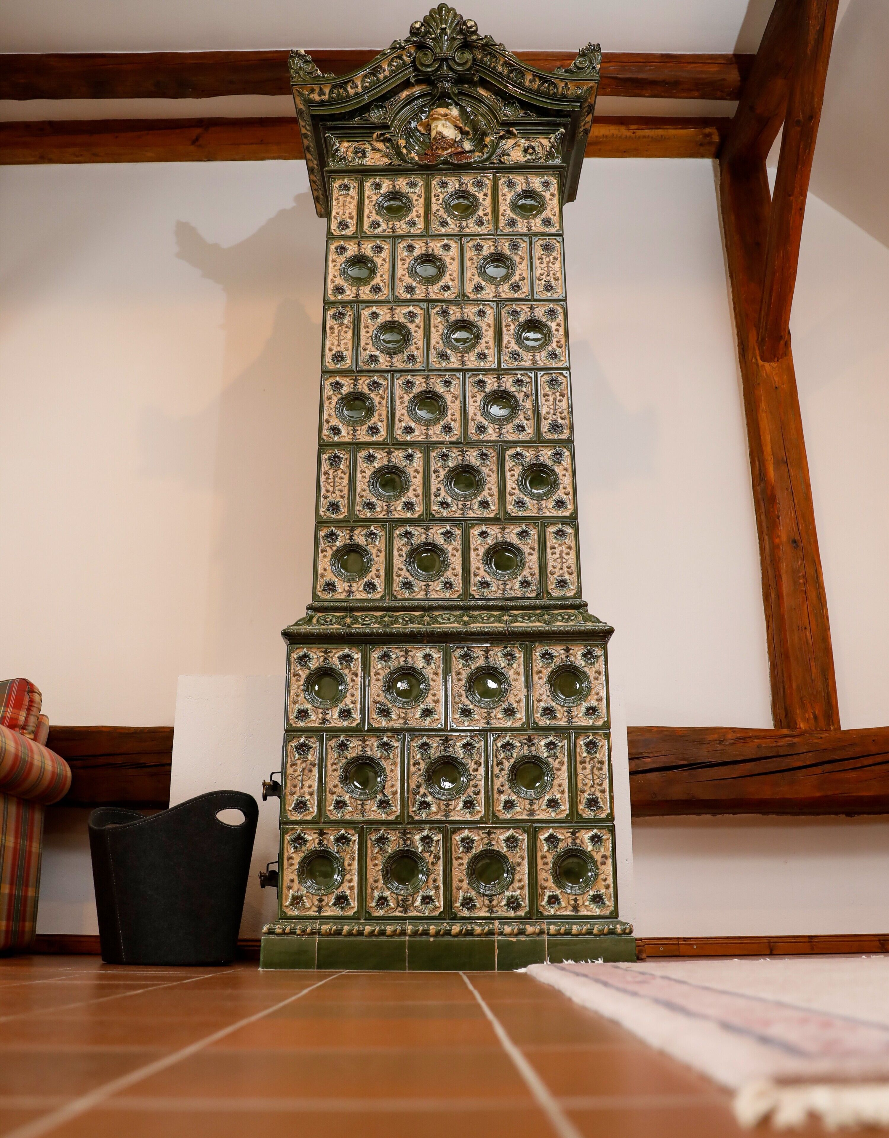 Un grand meuble richement décoré, orné de motifs floraux, se trouve dans une pièce dont le plafond est constitué de poutres en bois.