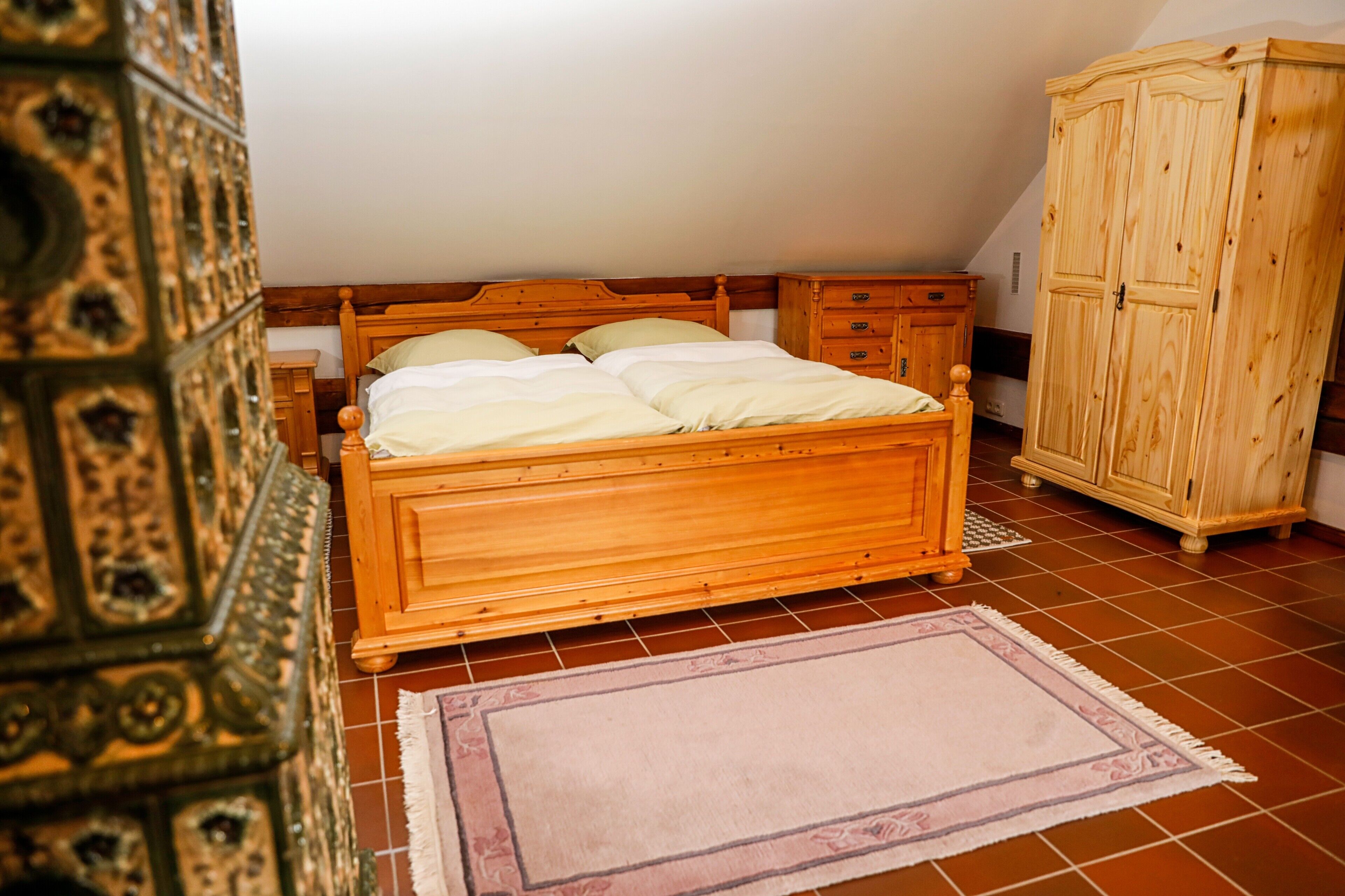 Un dormitorio con cama de madera, mesita de noche, armario y alfombra estampada.
