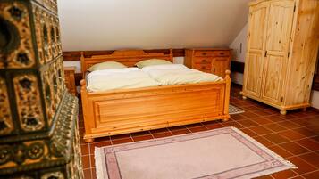 Un dormitorio con cama de madera, mesita de noche, armario y alfombra estampada.