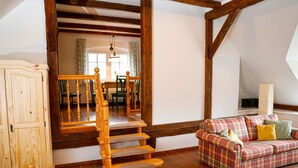 Un salon avec un canapé à carreaux, un escalier en bois et un meuble.