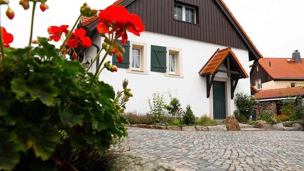 Une maison traditionnelle avec une allée pavée, des volets verts et un chemin de pierre.