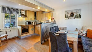 A modern kitchen with wooden cabinets, a dining area with a table and chairs, and a living area with a sofa.