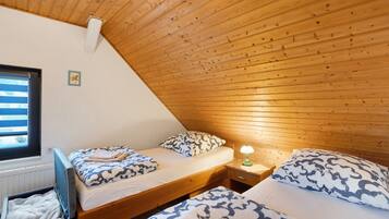 Ein Schlafzimmer mit zwei Betten, Holzboden, einem Fenster und einem Nachttisch mit Lampe.