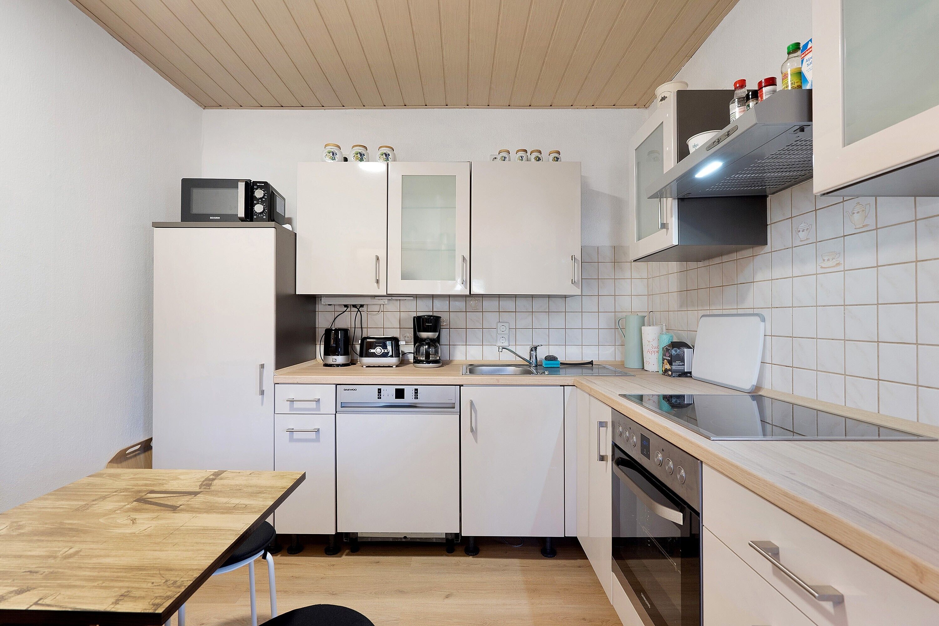 A compact kitchen with white cabinets, a dishwasher, a microwave, and a coffee maker.