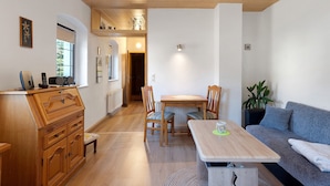 Une pièce comprenant une commode en bois, une table à manger avec des chaises, un canapé et une plante en pot.