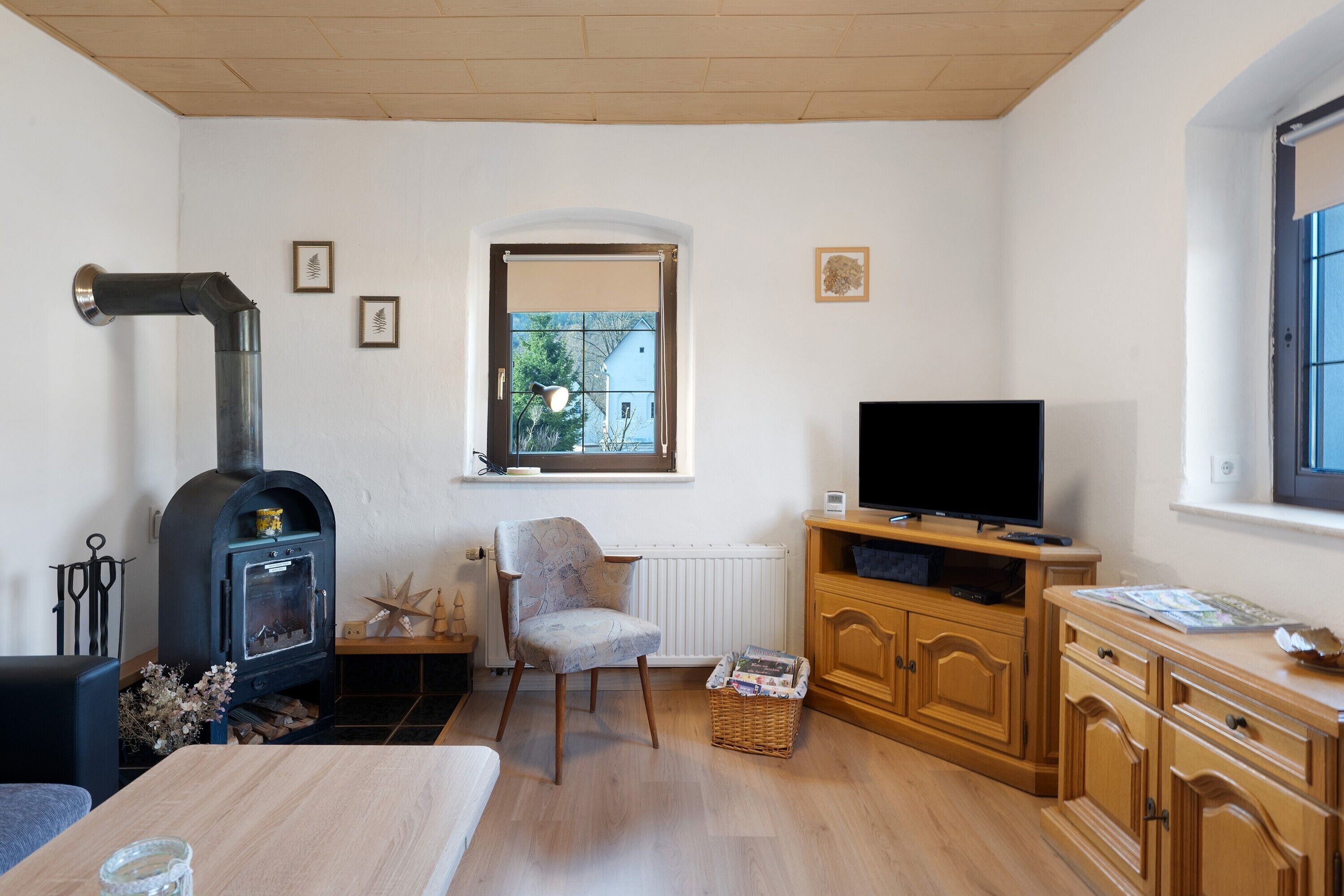 A living room with a fireplace, a television, wooden cabinets, and a window.