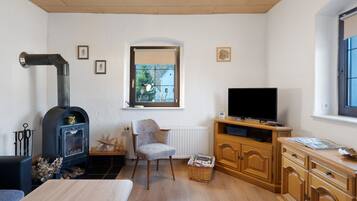 A living room with a fireplace, a television, wooden cabinets, and a window.