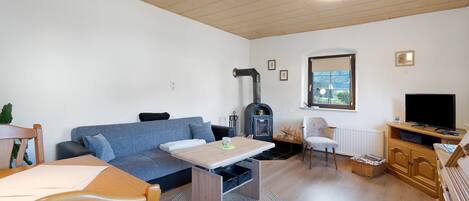 Una sala de estar con sofá, mesa, televisor, chimenea y ventana.