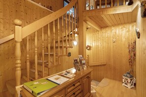A wooden interior with a staircase, wooden walls, a reception desk with brochures, and a small lantern.