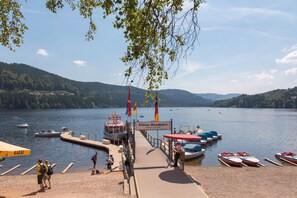 A lakeside dock with boats, a pier, and a sign indicating a location. - Apartment 'Ferienwohnung Bergidylle, 85qm' with Shared Terrace, Shared Garden and Wi-Fi (Schonach)