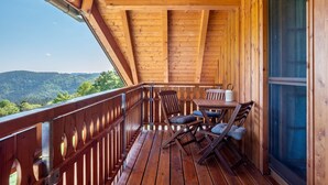 A wooden deck with a table and chairs, a railing, and a view of the mountains. - Apartment 'Panoramic View, 85sqm' with Shared Terrace, Garden and Wi-Fi (Schonach)