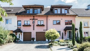 Una hilera de casas de dos pisos con un jardín central y un pequeño árbol.
