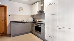 Una cocina moderna con electrodomésticos de acero inoxidable, un reloj en la pared y una puerta de madera.