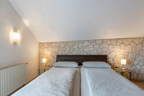 Un dormitorio con dos camas, pared de piedra y lámparas de noche.