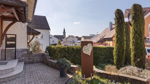 A residential area with a paved courtyard, a heart-shaped sign, and neatly trimmed hedges.