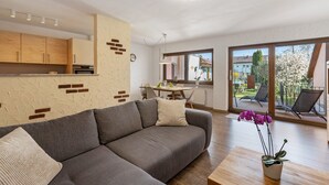 A modern living room with a grey sofa, a wooden coffee table, and a potted orchid.