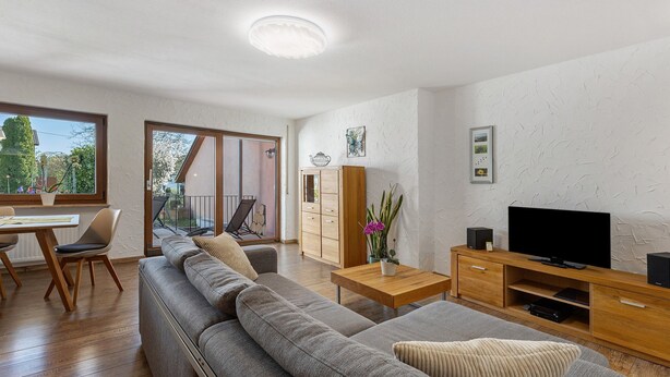 A modern living room with a sofa, TV stand, and dining area.