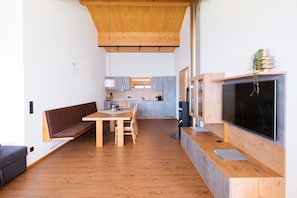Ein modernes Interieur mit einem Holzes Esstisch, einer Bank und einem Fernseher.