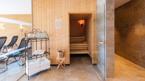 Een sauna met houten wanden, een glazen deur, een metalen rek met handdoeken en een houten bank.
