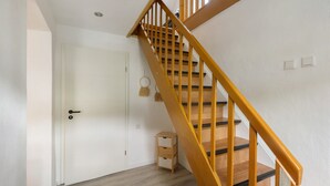 Een trap met houten leuningen en een witte deur met een sleutelgat.