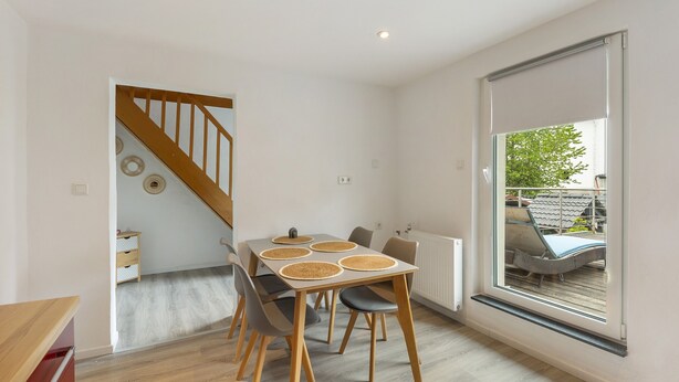 Een eethoek met een tafel, stoelen en uitzicht op de omgeving door een groot raam.