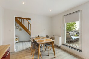 Un espace repas comprenant une table, des chaises et une vue sur l’extérieur grâce à une grande fenêtre.