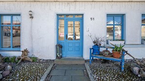 A building with a blue door, numbered 51, and a bench with potted plants outside. - Holiday Apartment 'Blütenzauber' with Wi-Fi (Sagard)
