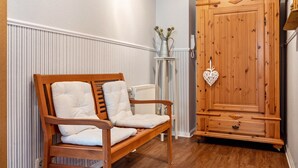 A wooden bench with cushions, a radiator, and a wooden wardrobe with a heart-shaped decoration. - Holiday Apartment 'Blütenzauber' with Wi-Fi (Sagard)
